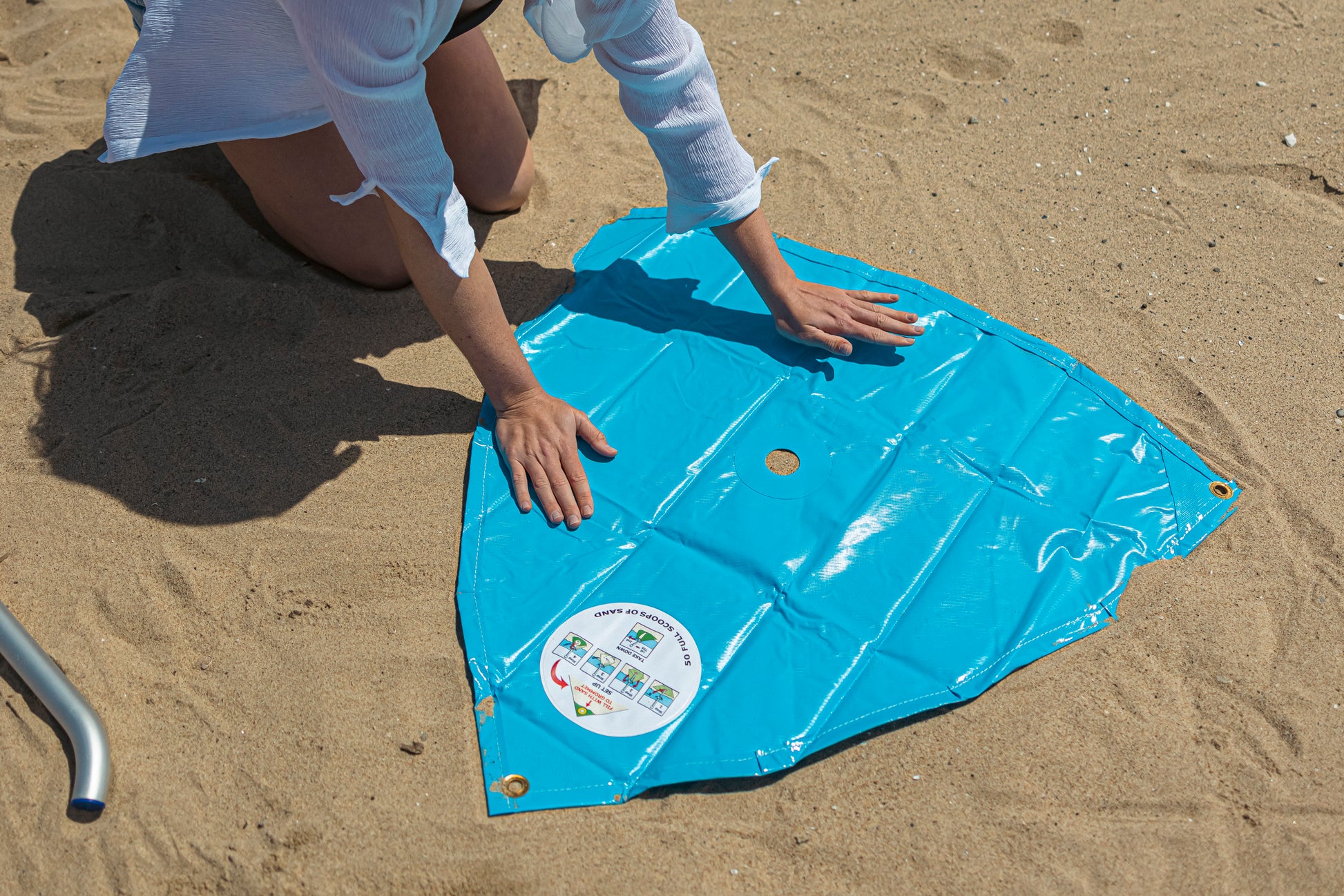 woman laying out the beach umbrella wind resistant base at the beach