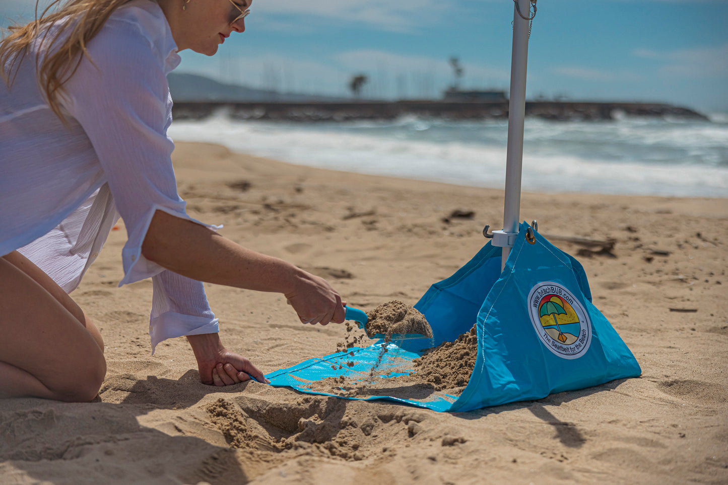 woman adding sand to ultimate beach umbrella base