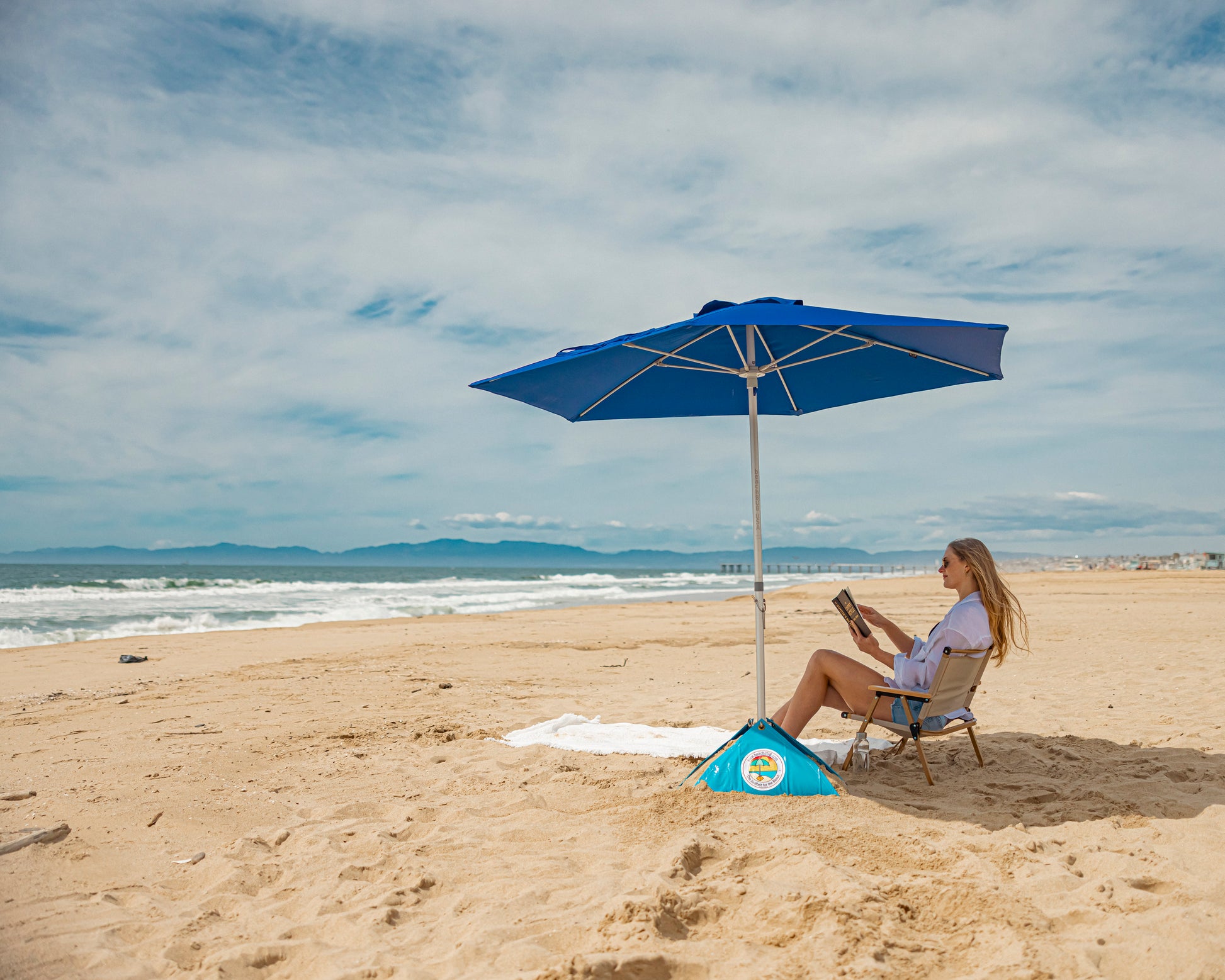 woman reading a book under a windproof beach umbrella